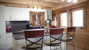 Una cocina con armarios de madera, una estufa y taburetes de bar.