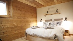 Dormitorio de cabaña de madera con una cama, almohadas y una mesita de noche.