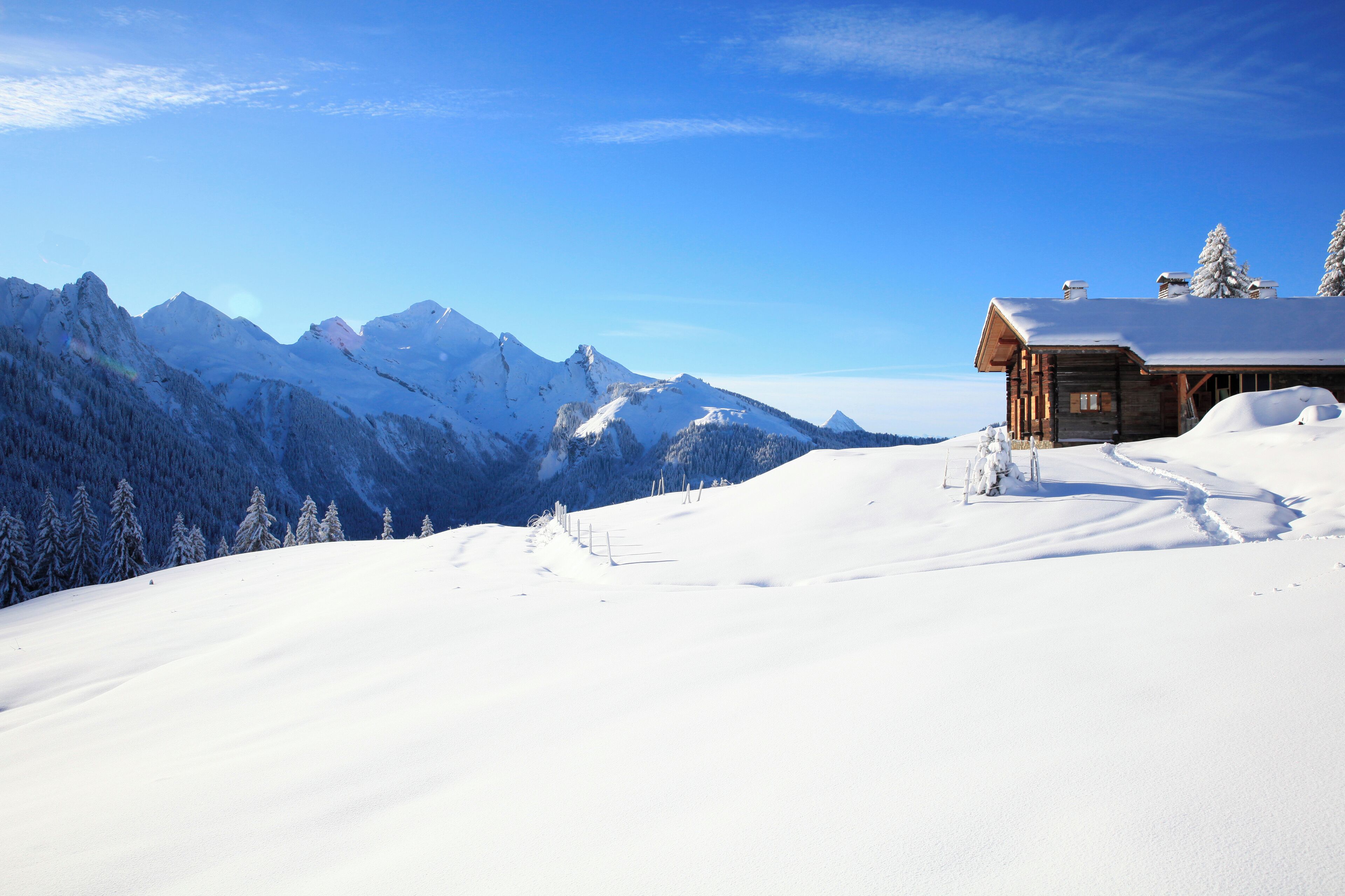 A snow-covered mountain landscape with a wooden cabin.