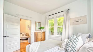 Una camera da letto con un letto grande, una cassettiera in legno, uno specchio e una finestra con tende.