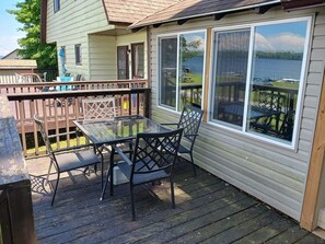 Una terraza con una mesa y sillas de vidrio, con vista a un lago.
