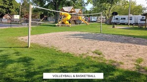 Canchas de voleibol y baloncesto en el Lake Consecon Resort, con un parque infantil y vehículos recreativos al fondo.