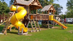 Un parque infantil con un tobogán amarillo y estructuras de juego de madera.
