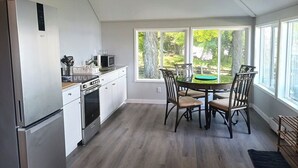 Una cocina moderna con armarios blancos, electrodomésticos de acero inoxidable y un comedor con mesa y sillas.