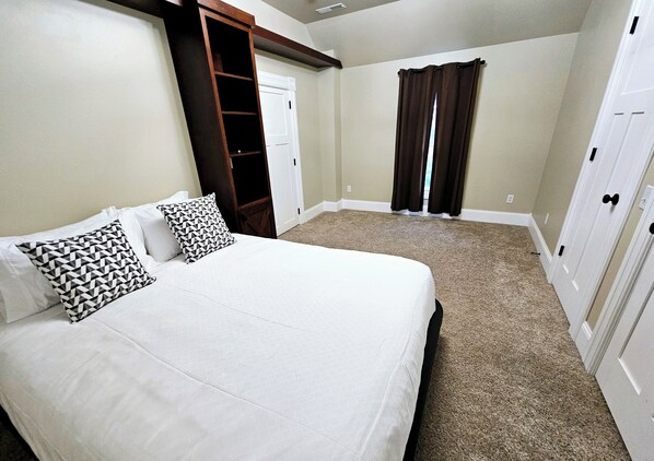 A bedroom with a large bed, a wardrobe, and a door leading to another room.