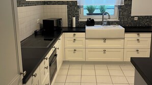 A modern kitchen with white cabinets, a black countertop, a window with a view, and a tiled backsplash. - Excellent connections to the trade fair, cathedral and old town by public transport, yet in a very quiet location  (Köln)