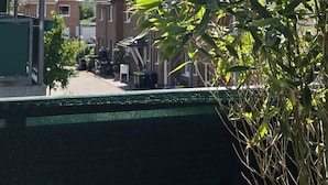 A residential area with houses, a green fence, and a tree with green leaves. - Excellent connections to the trade fair, cathedral and old town by public transport, yet in a very quiet location  (Köln)