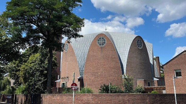 A building with three arched brick structures and a large tree in front. - Excellent connections to the trade fair, cathedral and old town by public transport, yet in a very quiet location  (Köln)