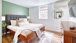 A bedroom with a wooden bed, bedside tables, a mirror, and a dresser. - Retro Hideaway - Trendy Location - 2BR - Sleeps 4 (Portland)