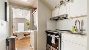 Una cocina compacta con armarios blancos, estufa de acero inoxidable y un lavamanos.