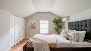 Un dormitorio con cama, ventana, planta y puerta.