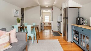 Un espacio habitable compacto con comedor, kitchenette y un dormitorio visible al fondo.