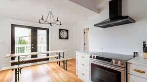 A kitchen with a built-in oven, white cabinetry, and a bench.