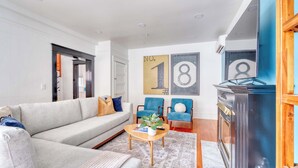 A modern living room with a grey sofa, two blue armchairs, a wooden coffee table, and a fireplace.