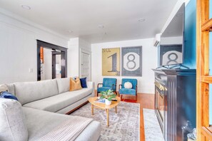 A modern living room with a grey sofa, two blue armchairs, a wooden coffee table, and a fireplace.