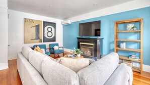 A living room with a sofa, a fireplace, a TV, and a bookshelf.