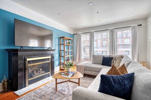A living room with a fireplace, a sofa, a coffee table, and a bookshelf.