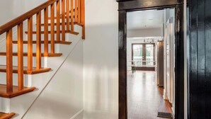 A wooden staircase leading to a balcony with a view, a modern ceiling light, and a clean, well-lit interior.