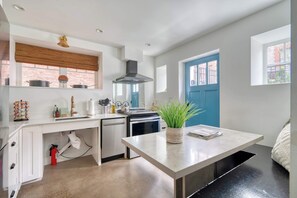 A modern kitchen with white cabinetry, a built-in stove, and a blue door. - Massive 7BR - Nob Hill - NW 23rd - Sleeps 14 (Portland)