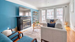 A living room with a fireplace, a sofa, a coffee table, and a bookshelf. - Massive 7BR - Nob Hill - NW 23rd - Sleeps 14 (Portland)
