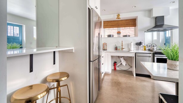 A modern kitchen with a stainless steel refrigerator, white cabinetry, a wooden window blind, and a potted plant on the counter. - 1906 3BR Retreat • NW 23rd Boutiques & Eats (Portland)