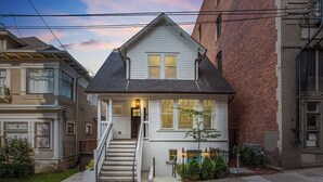 A two-story house with a front porch, a staircase, and a small tree in the front yard. - 1906 3BR Retreat • NW 23rd Boutiques & Eats (Portland)