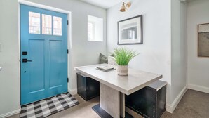 A hallway with a blue door, a light switch, a framed picture, and a potted plant. - 1906 3BR Retreat • NW 23rd Boutiques & Eats (Portland)