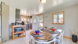 A modern kitchen with a wooden dining table, white chairs, and a built-in microwave. - Houghton Lake Cottage w/ Patio: Walk to Waterfront (Houghton Lake)