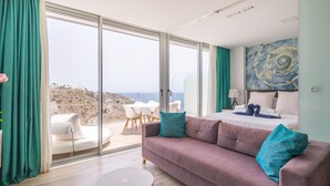 Una habitación de hotel moderna con un balcón amplio, una cama, un sofá y un área de comedor.