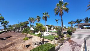 Un resort con palmeras, asientos al aire libre y vista al océano.