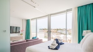 Una habitación de hotel moderna con una cama grande, un sofá, un televisor y un balcón con vistas a la ciudad.