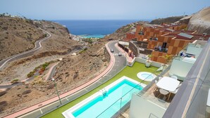 Zona de piscina con vista al océano y un camino serpenteante.