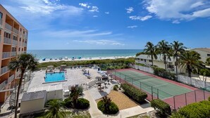 Ett semesterhotell med pool, tennisbanor och utsikt över stranden.