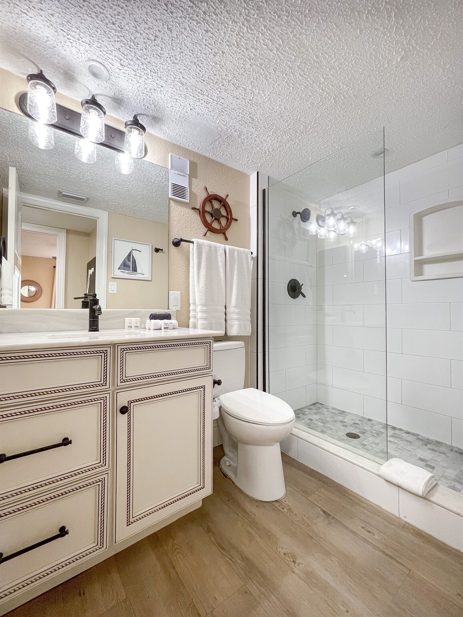 A bathroom with a vanity, toilet, and a glass shower enclosure.