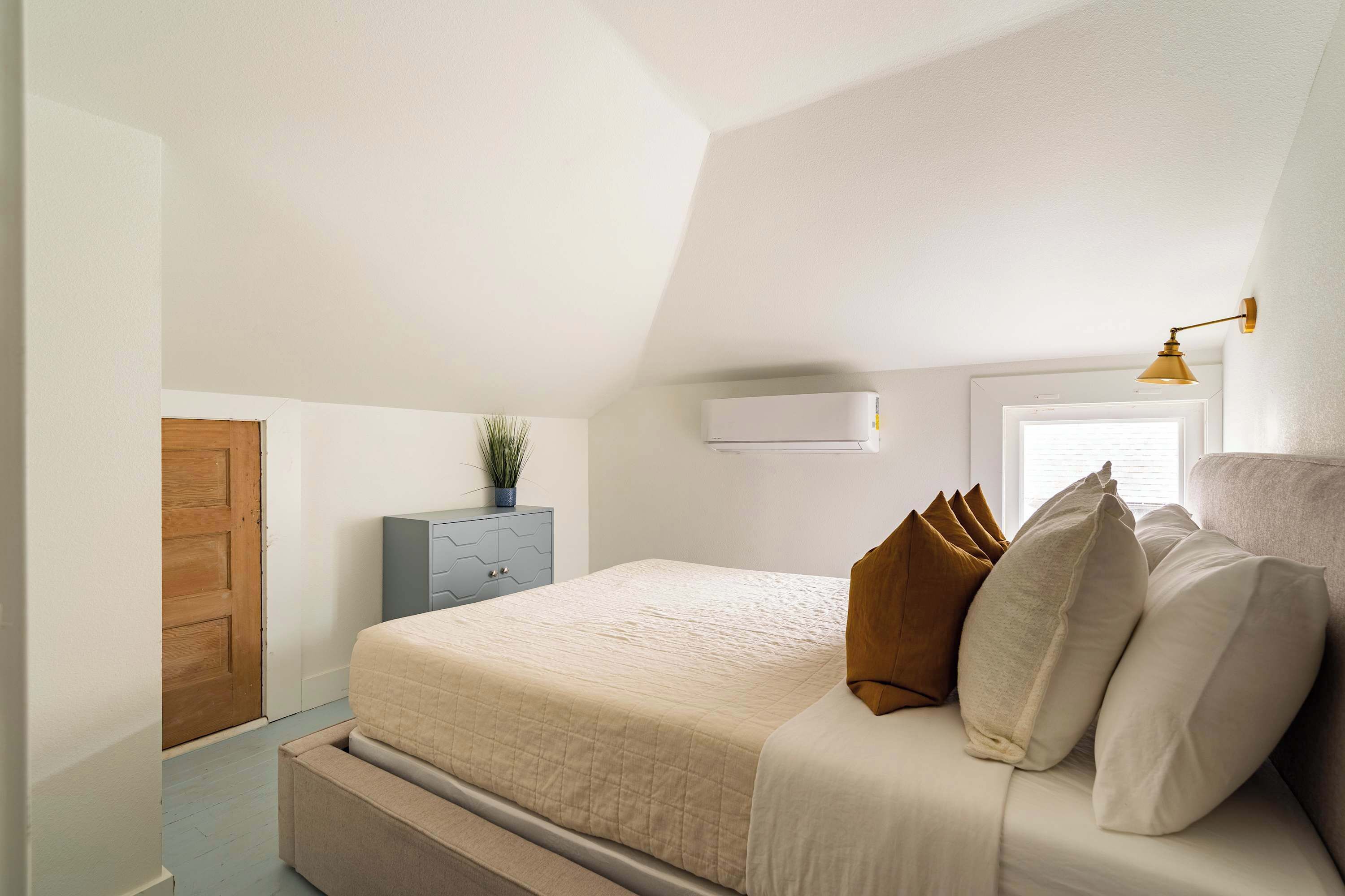 A bedroom with a bed, a dresser, a window, and a ceiling light.