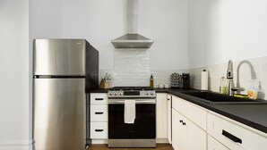 Une cuisine moderne dotée d’appareils électroménagers en acier inoxydable, d’une cuisinière à gaz et de meubles de rangement blancs.