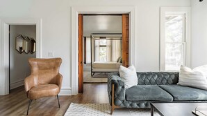 Un salon moderne avec un fauteuil en cuir, un canapé capitonné et une décoration minimaliste.