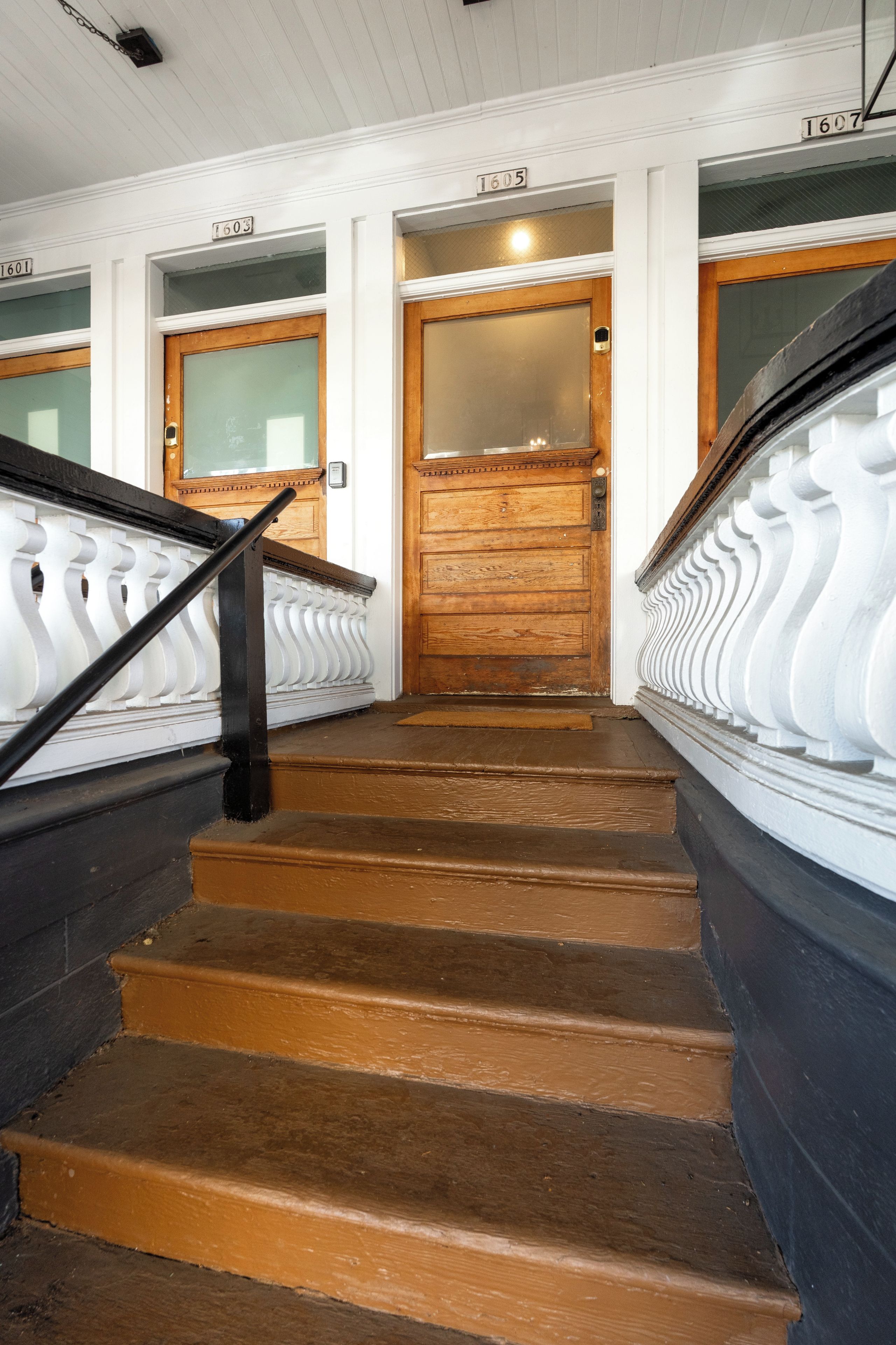 A staircase with wooden steps and white balustrades leading to a wooden door.