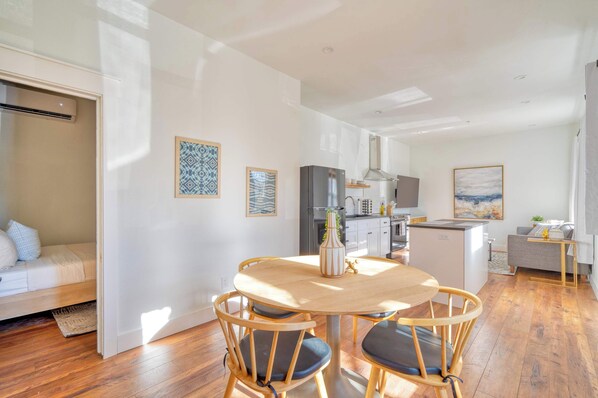 A modern kitchen with a central island, wooden chairs, and a dining table.