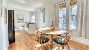 A modern kitchen with wooden flooring, a dining table with two chairs, and a refrigerator. - 1BR • Fast WiFi • Walk to Dining & Breweries (Portland)
