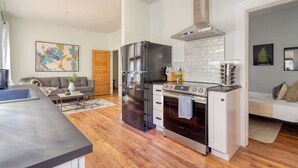 A modern kitchen with a stainless steel refrigerator, oven, and stove, wooden flooring, and a gray countertop. - 1BR - Boutique Flat - Prime NW Location (Portland)