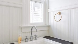 Un baño blanco con lavamanos blanco, encimera negra y muebles blancos.