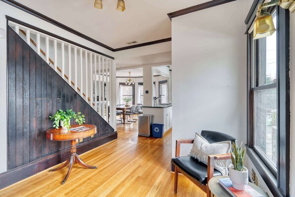 A modern interior with a wooden staircase, a dining area, and a view through a window.