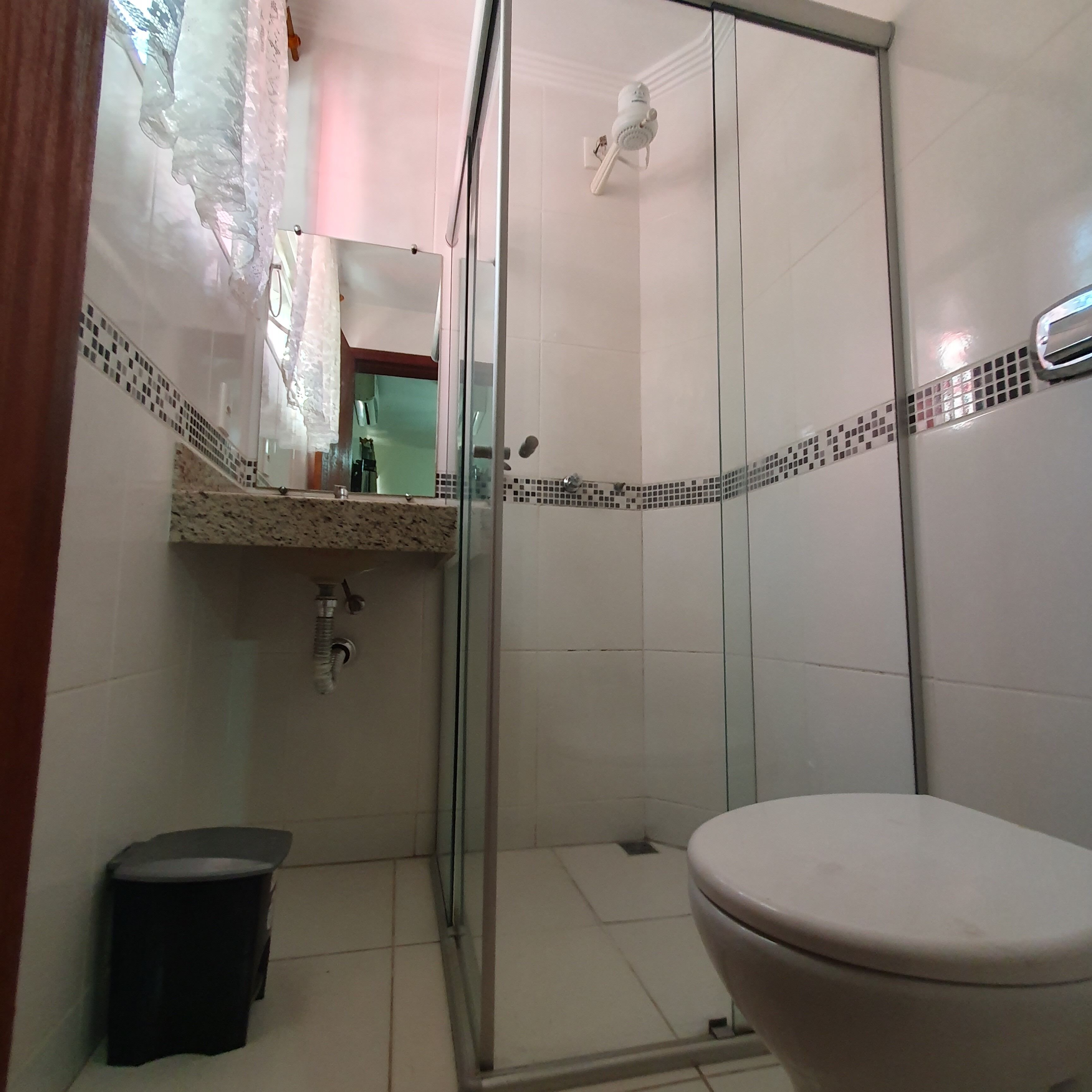 Un baño con cabina de ducha de vidrio, inodoro y lavabo con espejo.