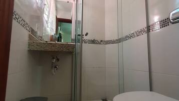 Un baño con cabina de ducha de vidrio, inodoro y lavabo con espejo.