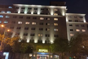 Un hôtel à plusieurs étages, doté de fenêtres illuminées et d’une entrée au niveau du sol.