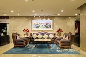 A lobby with a reception desk, a sofa set, a large framed picture, and a decorative vase. - Ordos Aili Hotel (Beijing Jinbao Street) (Beijing)