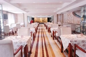 Un restaurante con mesas largas, una barra central y una decoración de estilo moderno.