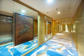 A hotel corridor with a patterned carpet, glass walls, and a framed artwork. - Ordos Aili Hotel (Beijing Jinbao Street) (Beijing)
