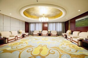 Una habitación amplia con un gran alfombra redonda, un candelabro y varias zonas de estar.